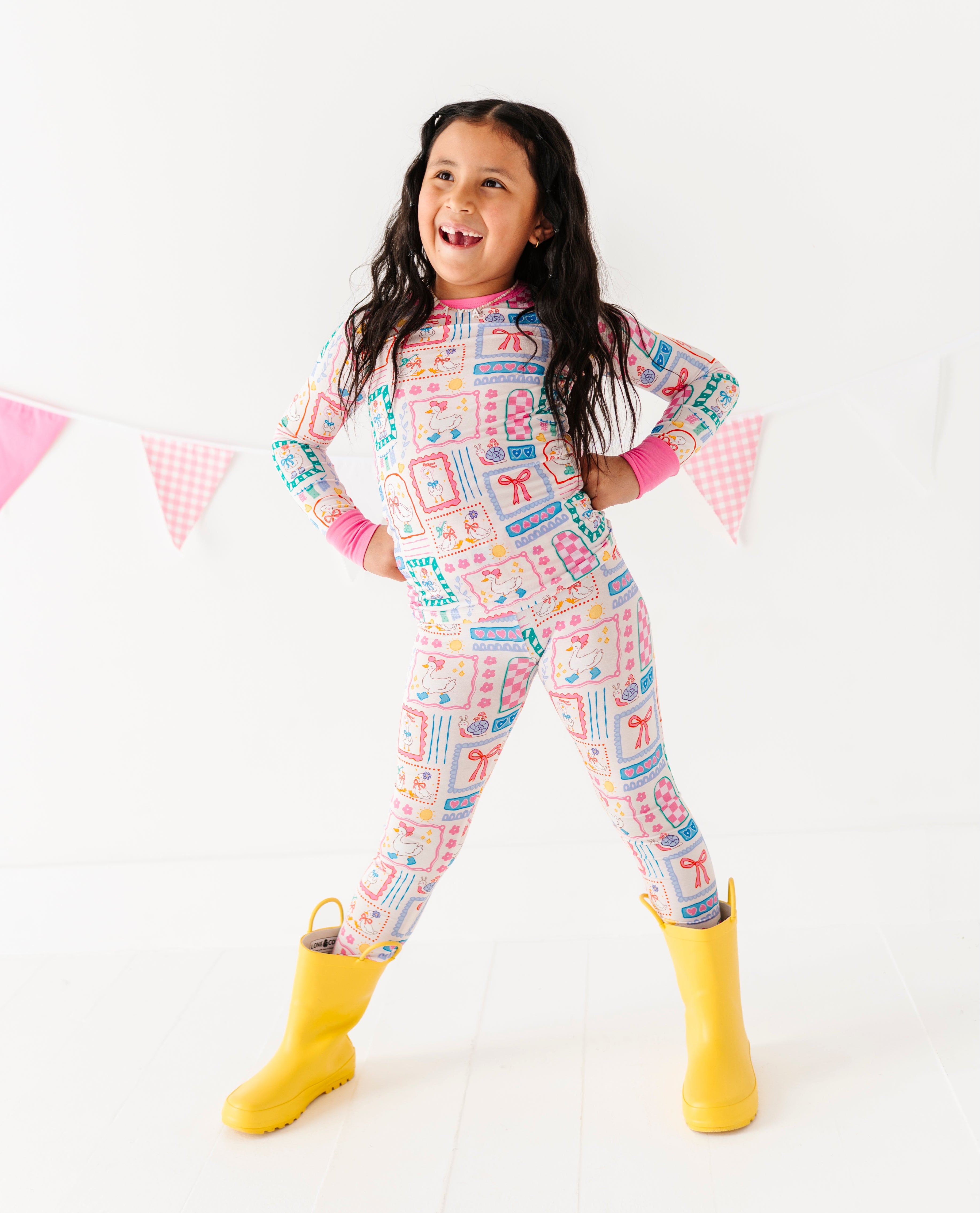 Child wearing colorful patterned pajamas with yellow boots on a white background